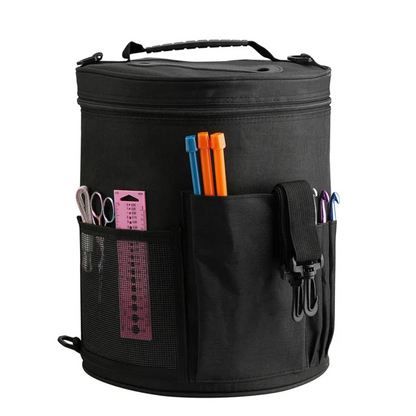 The Yarn Organizer Bag (Bundle9) is a black cylindrical craft bag with a handle, equipped with multiple outside pockets designed to hold rulers, scissors, crochet hooks, and pens. It's ideal for knitters and crocheters who want to keep their crafting supplies neatly organized and within easy reach.
